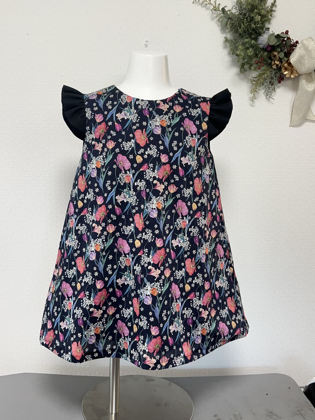 紺地の小花柄と黒いフリル袖の子ども用ワンピース