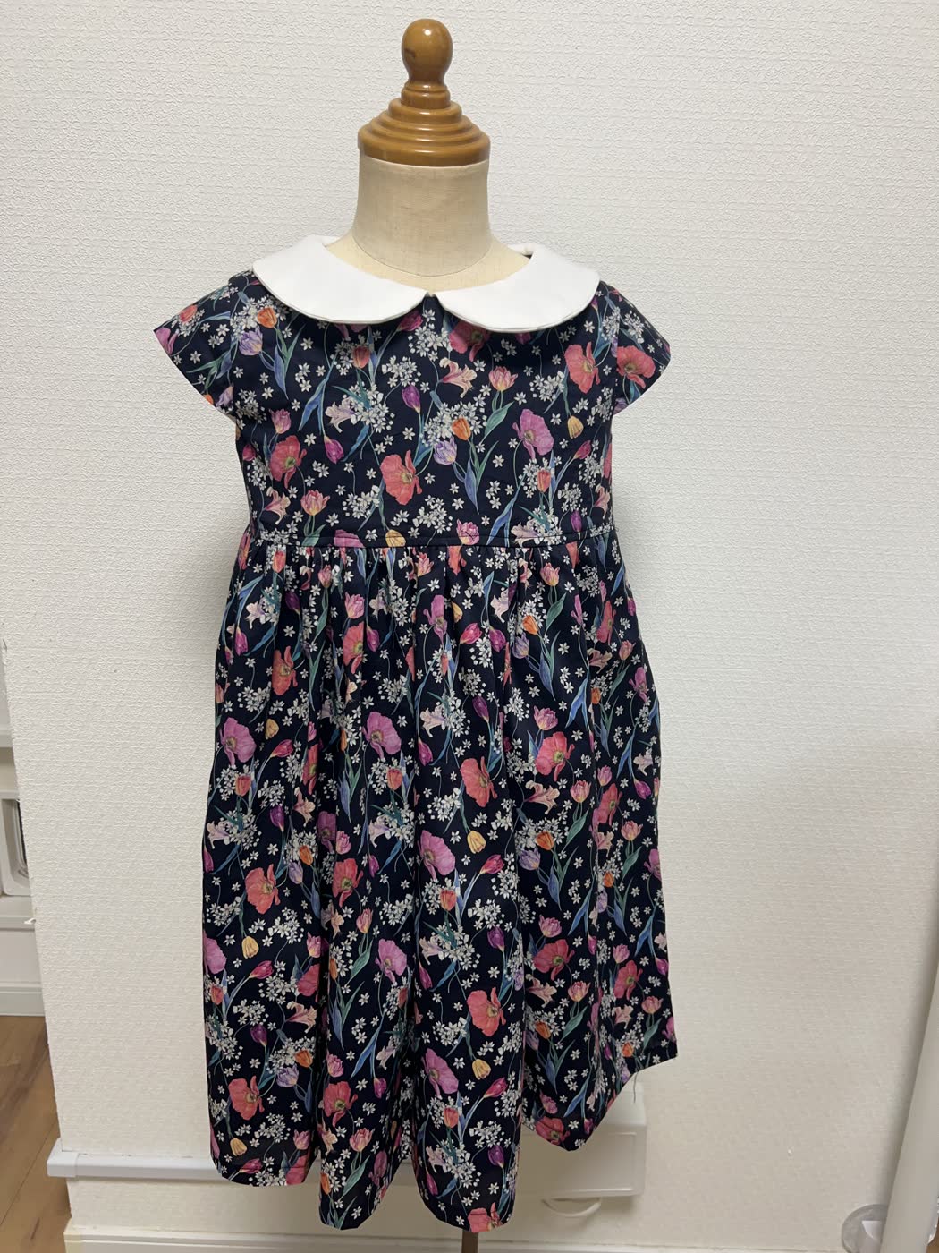 白い襟と紺地の花柄を組み合わせた子ども用ワンピース